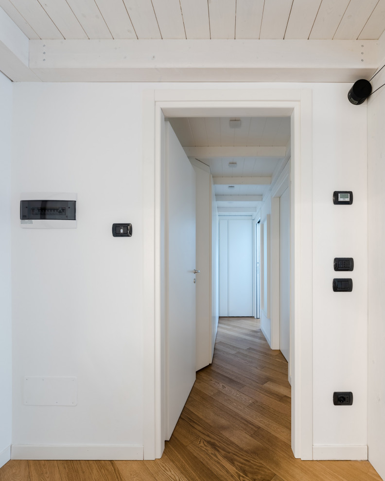 Idéer för små nordiska hallar, med vita väggar, laminatgolv och brunt golv