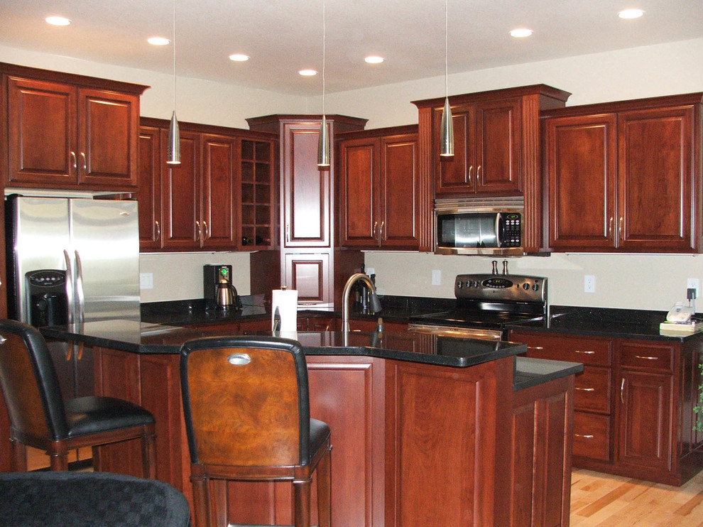 Inspiration for a mid-sized timeless l-shaped eat-in kitchen remodel with an undermount sink, raised-panel cabinets, medium tone wood cabinets, stainless steel appliances and an island