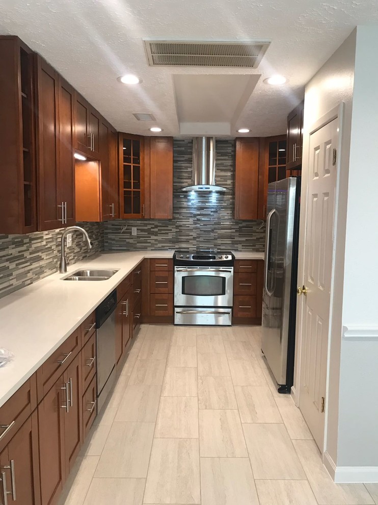 Example of a mid-sized transitional u-shaped porcelain tile and gray floor enclosed kitchen design in Houston with an undermount sink, shaker cabinets, medium tone wood cabinets, quartz countertops, multicolored backsplash, glass tile backsplash, stainless steel appliances, no island and white countertops