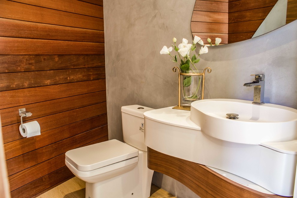 This is an example of a small contemporary powder room in Los Angeles with a two-piece toilet, grey walls, light hardwood floors, a vessel sink, solid surface benchtops, beige floor, white benchtops, flat-panel cabinets and white cabinets.
