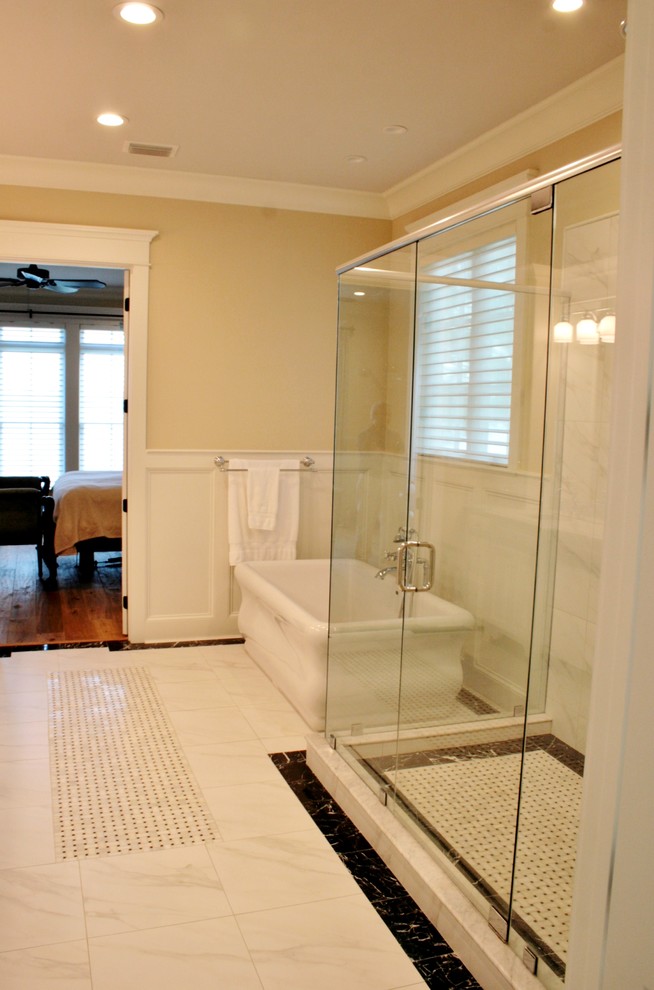 Photo of a master bathroom in Miami with an undermount sink, raised-panel cabinets, white cabinets, marble benchtops, a freestanding tub, a double shower, a one-piece toilet, white tile, beige walls and ceramic floors.