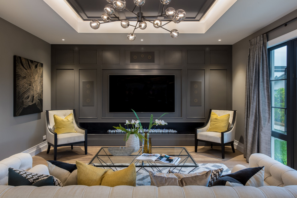 Large transitional formal enclosed living room in Auckland with grey walls, medium hardwood floors, a wall-mounted tv, brown floor, a ribbon fireplace and a wood fireplace surround.