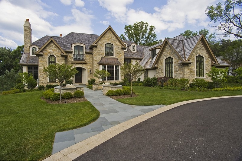 Photo of an expansive traditional two-storey beige exterior in Chicago with stone veneer and a gable roof.