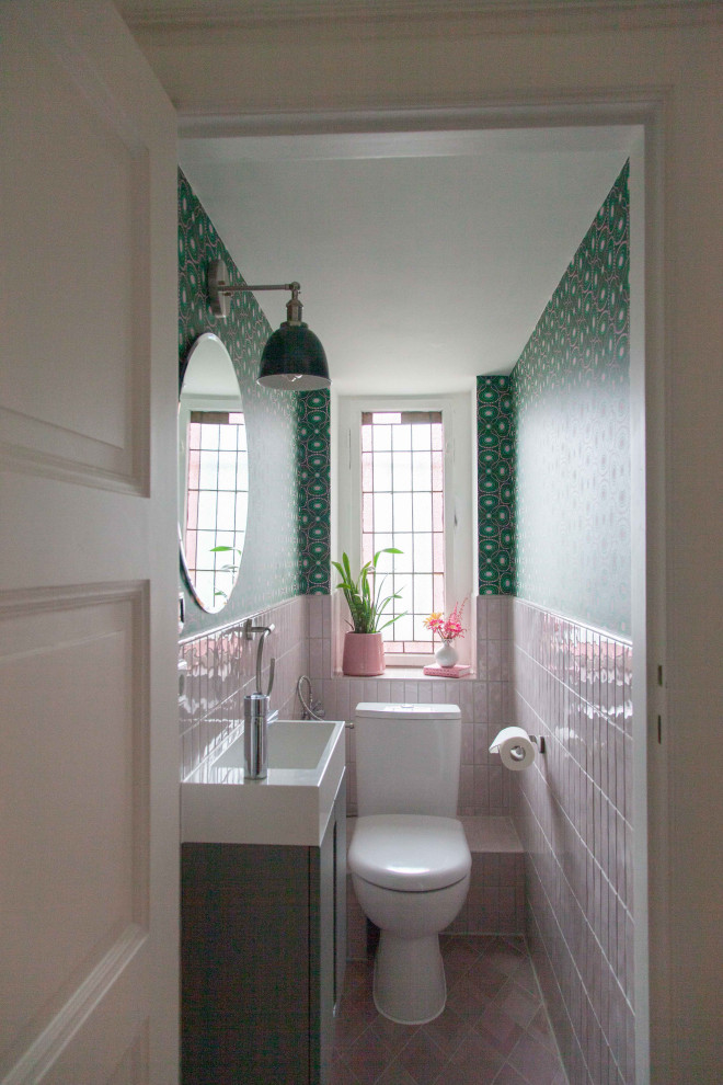 Inspiration for a small eclectic master bathroom in Berlin with flat-panel cabinets, grey cabinets, a one-piece toilet, pink tile, ceramic tile, green walls, ceramic floors, an integrated sink, laminate benchtops, pink floor, white benchtops, an enclosed toilet, a single vanity, a floating vanity and wallpaper.