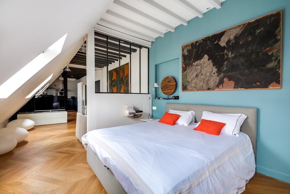 This is an example of a mid-sized contemporary bedroom in Paris with blue walls and medium hardwood floors.
