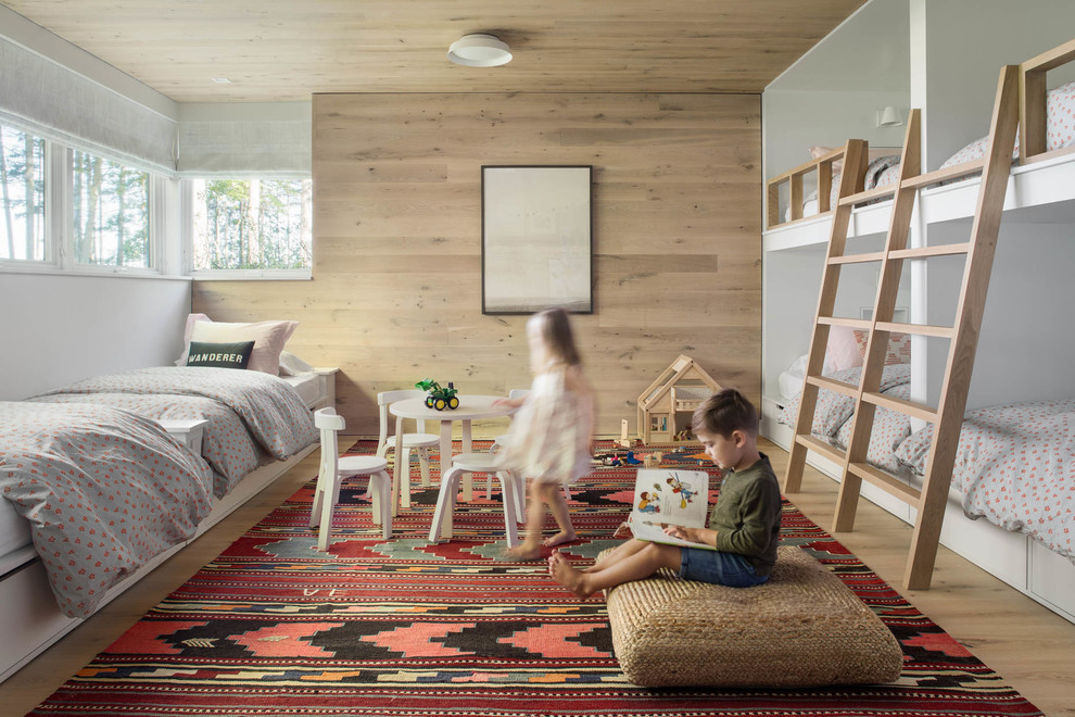 Photo of a modern gender-neutral kids' bedroom for kids 4-10 years old in Portland Maine with beige walls, light hardwood floors and beige floor.