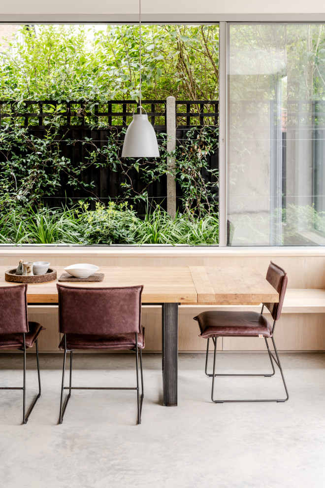 Aménagement d'une salle à manger moderne de taille moyenne avec une banquette d'angle, un mur blanc, sol en béton ciré et un sol gris.