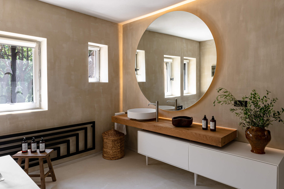 Bild på ett funkis brun brunt en-suite badrum, med släta luckor, vita skåp, ett fristående badkar, bruna väggar, träbänkskiva och beiget golv