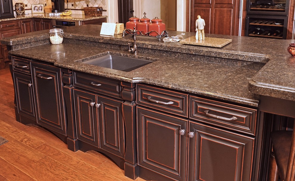 Example of a large transitional u-shaped dark wood floor eat-in kitchen design with an island, raised-panel cabinets, dark wood cabinets, beige backsplash, stainless steel appliances, an undermount sink, granite countertops and ceramic backsplash