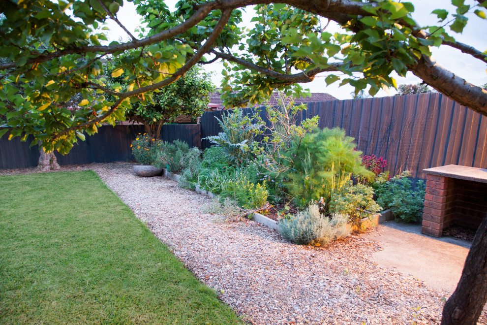 Large contemporary backyard full sun garden with a vegetable garden and mulch for spring.