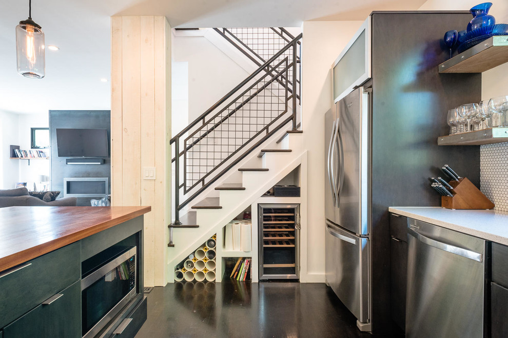 Trendy dark wood floor and black floor kitchen photo with ceramic backsplash, stainless steel appliances and an island