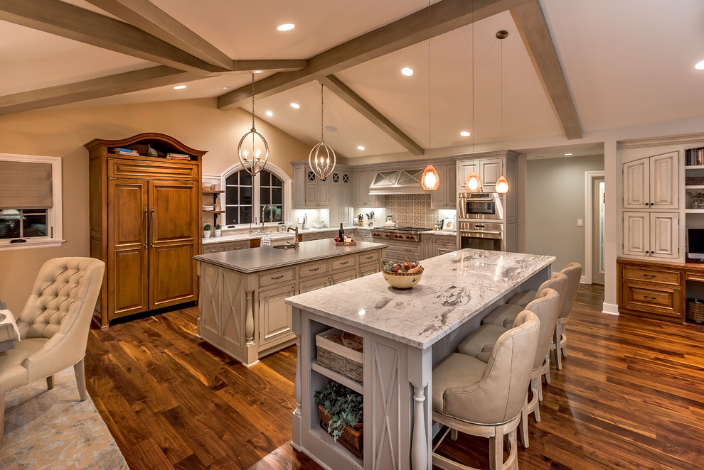 This is an example of a traditional l-shaped open plan kitchen in San Francisco with raised-panel cabinets, grey cabinets, multi-coloured splashback, stainless steel appliances, dark hardwood floors and multiple islands.
