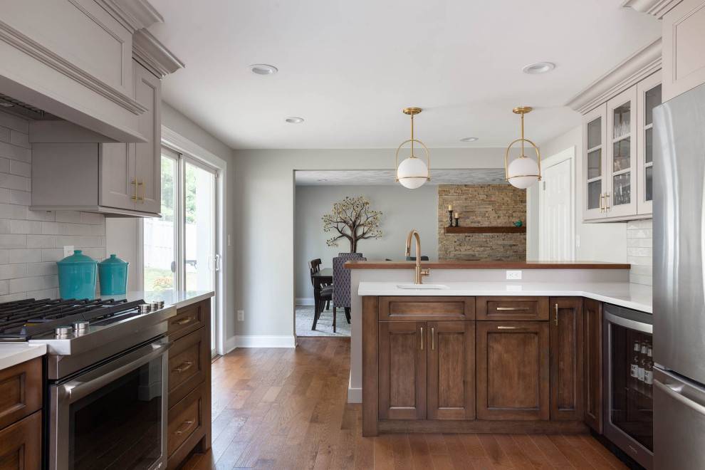 Kitchen - transitional medium tone wood floor kitchen idea with recessed-panel cabinets, quartz countertops, subway tile backsplash, stainless steel appliances and a peninsula
