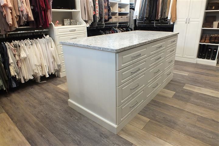 Photo of an expansive contemporary gender-neutral walk-in wardrobe in Cleveland with raised-panel cabinets, white cabinets, vinyl floors and brown floor.