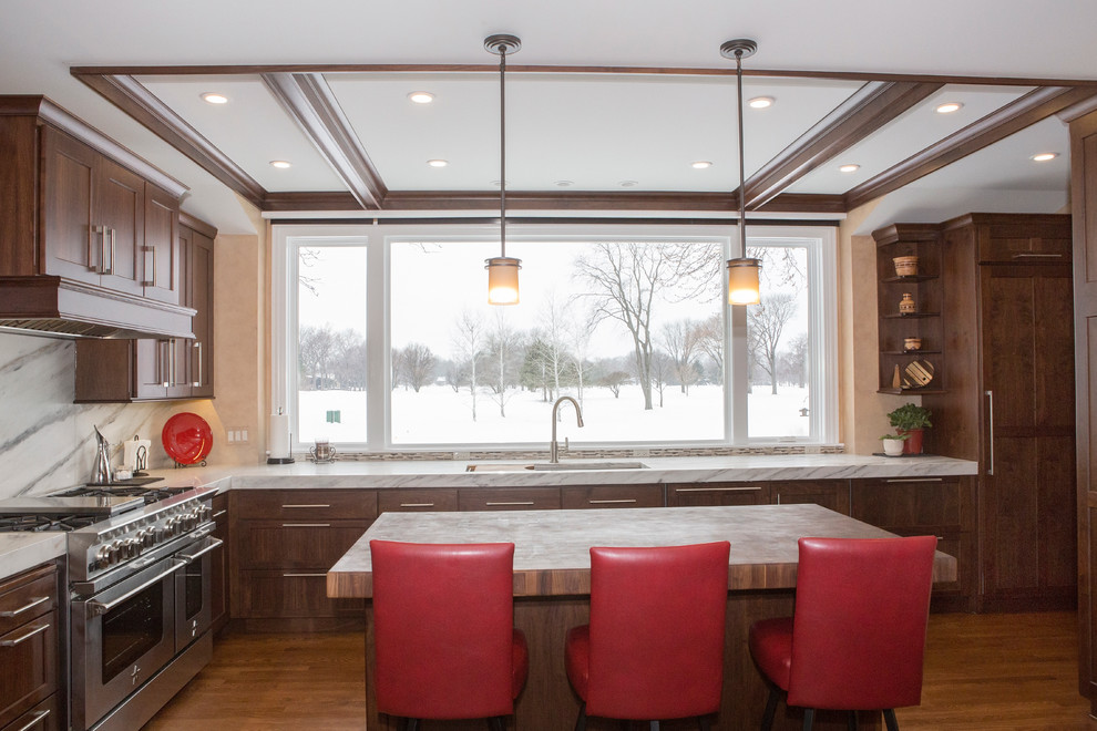 Example of a huge transitional l-shaped medium tone wood floor enclosed kitchen design in Chicago with an undermount sink, flat-panel cabinets, medium tone wood cabinets, marble countertops, white backsplash, stone slab backsplash, stainless steel appliances and an island