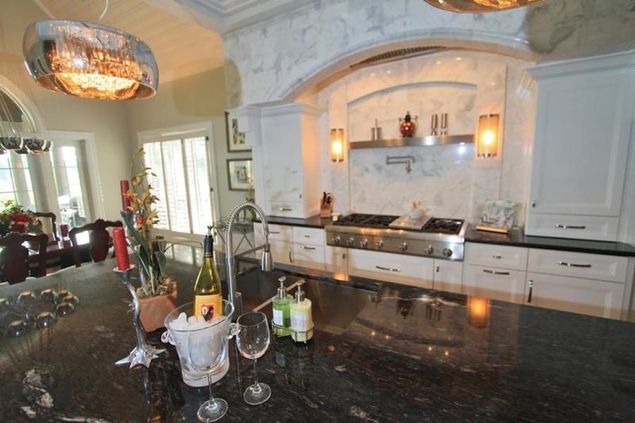 Inspiration for a mid-sized transitional galley eat-in kitchen remodel with a double-bowl sink, louvered cabinets, white cabinets, granite countertops, white backsplash, stone slab backsplash, stainless steel appliances and an island