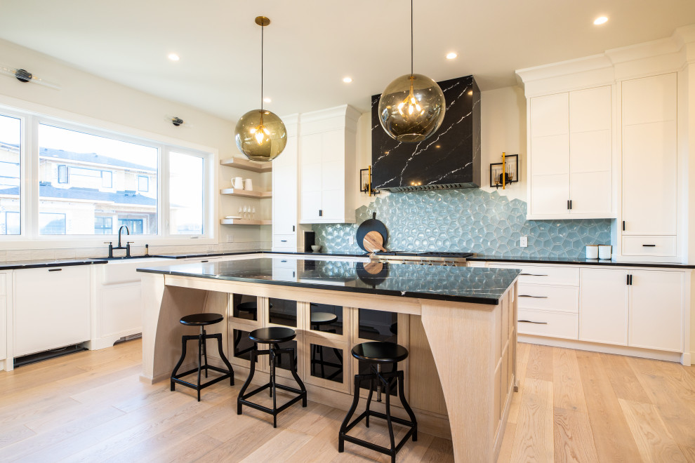 Large country u-shaped eat-in kitchen in Calgary with an undermount sink, recessed-panel cabinets, white cabinets, marble benchtops, blue splashback, glass tile splashback, stainless steel appliances, plywood floors, with island, brown floor and black benchtop.