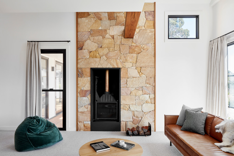 This is an example of a mid-sized country open concept living room in Melbourne with white walls, carpet, a wood stove, no tv, grey floor and a stone fireplace surround.