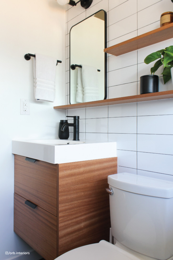 Photo of a mid-sized modern 3/4 bathroom in Denver with flat-panel cabinets, medium wood cabinets, white tile, white walls, solid surface benchtops, white benchtops, a single vanity and a floating vanity.