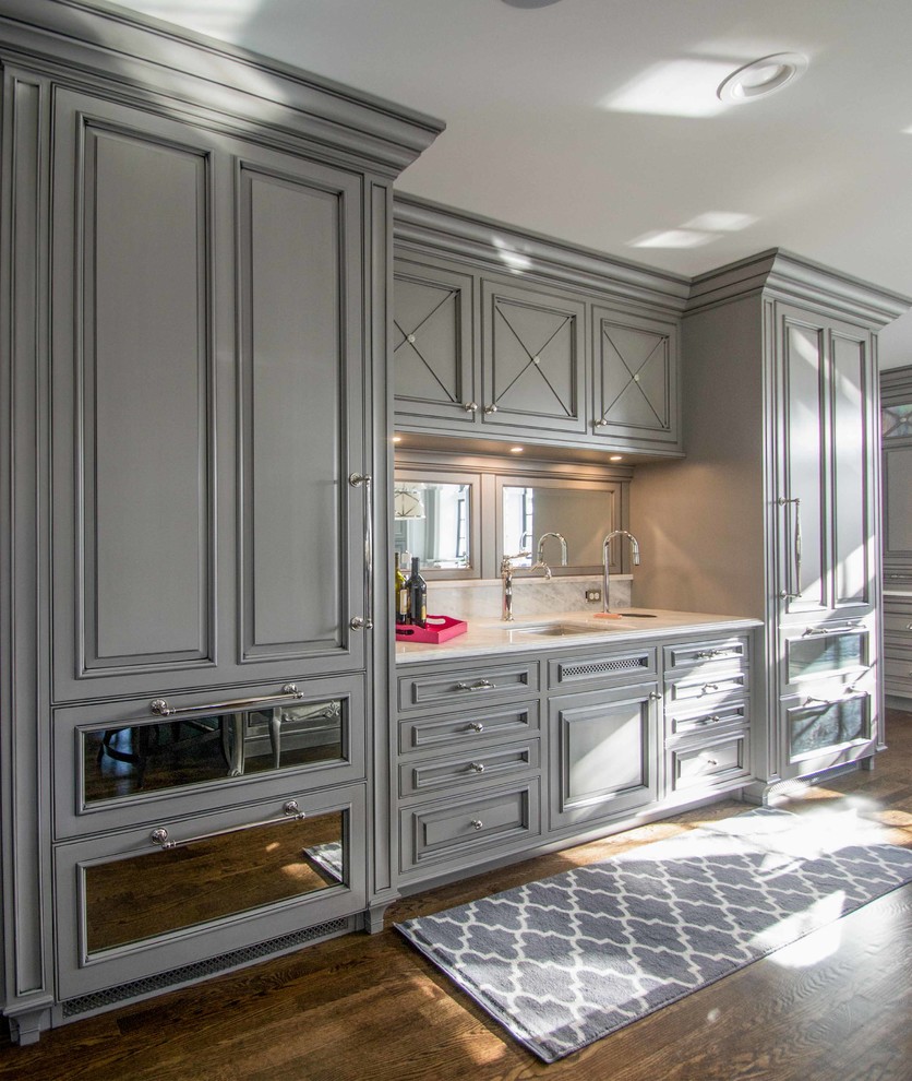 This is an example of an expansive traditional u-shaped open plan kitchen in Cedar Rapids with an undermount sink, grey cabinets, marble benchtops, white splashback, stainless steel appliances, dark hardwood floors, multiple islands and recessed-panel cabinets.