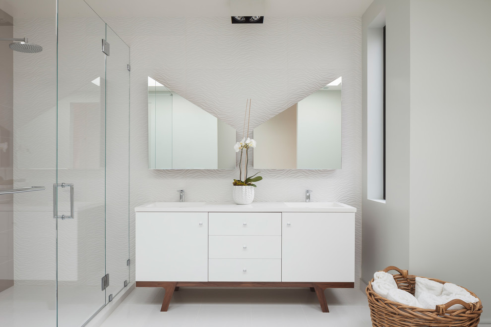 This is an example of a large contemporary master bathroom in San Francisco with an integrated sink, flat-panel cabinets, white cabinets, an alcove shower, white walls, a wall-mount toilet, white tile, porcelain tile, ceramic floors, engineered quartz benchtops, beige floor, a hinged shower door and white benchtops.