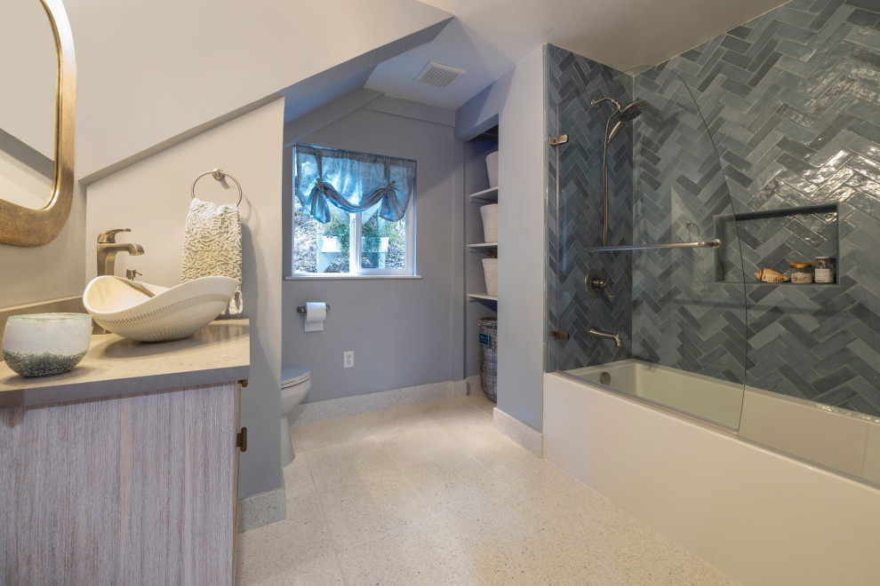 This is an example of a mid-sized beach style 3/4 bathroom in San Francisco with distressed cabinets, an alcove tub, a shower/bathtub combo, a two-piece toilet, blue tile, ceramic tile, grey walls, terrazzo floors, a vessel sink, engineered quartz benchtops, white floor, a hinged shower door, grey benchtops, a niche, a single vanity and a floating vanity.