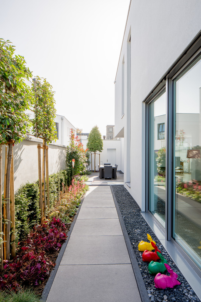 This is an example of a large contemporary side yard partial sun garden for summer in Dusseldorf with a container garden and concrete pavers.