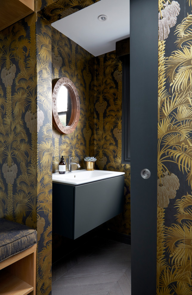 Mid-sized traditional powder room in London with flat-panel cabinets, black cabinets, a wall-mount toilet, multi-coloured walls, dark hardwood floors, a wall-mount sink, marble benchtops, black floor, white benchtops, a floating vanity and wallpaper.