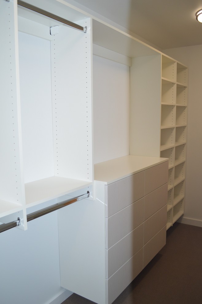 This is an example of a mid-sized contemporary gender-neutral walk-in wardrobe in Portland with flat-panel cabinets and white cabinets.
