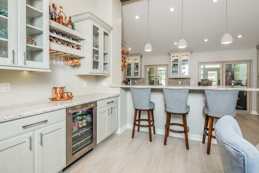 This is an example of a mid-sized transitional galley eat-in kitchen in San Diego with an undermount sink, shaker cabinets, beige cabinets, granite benchtops, beige splashback, porcelain splashback, stainless steel appliances, light hardwood floors and beige floor.