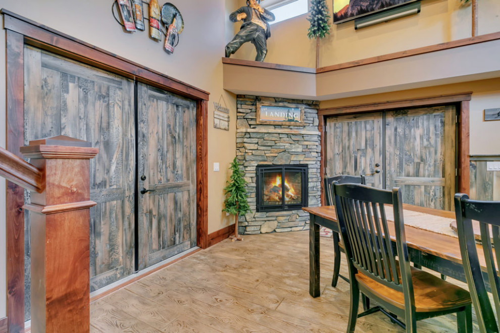Example of a mountain style concrete floor, beige floor and vaulted ceiling kitchen/dining room combo design in Minneapolis with a corner fireplace and a stacked stone fireplace