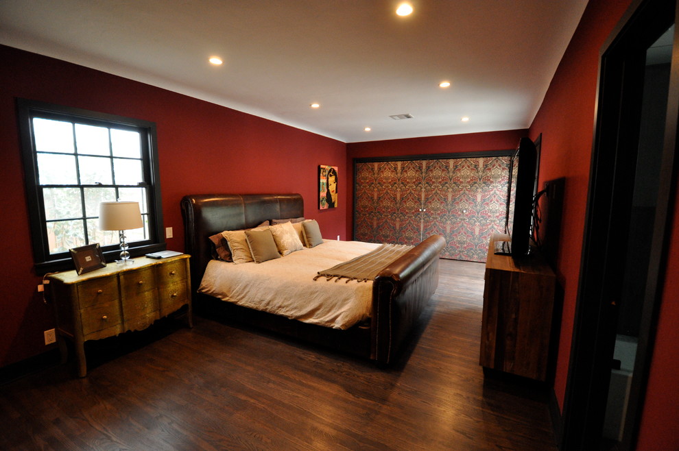 Large traditional master bedroom in Los Angeles with red walls, dark hardwood floors, no fireplace and brown floor.