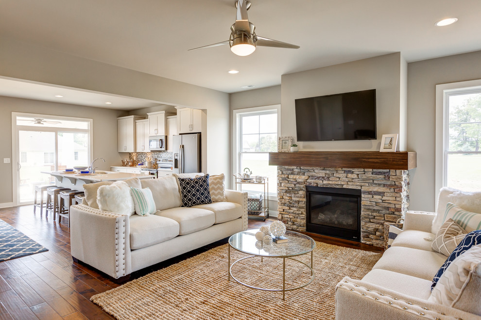 Mid-sized beach style open concept living room in Other with grey walls, medium hardwood floors, a standard fireplace, a stone fireplace surround and a wall-mounted tv.