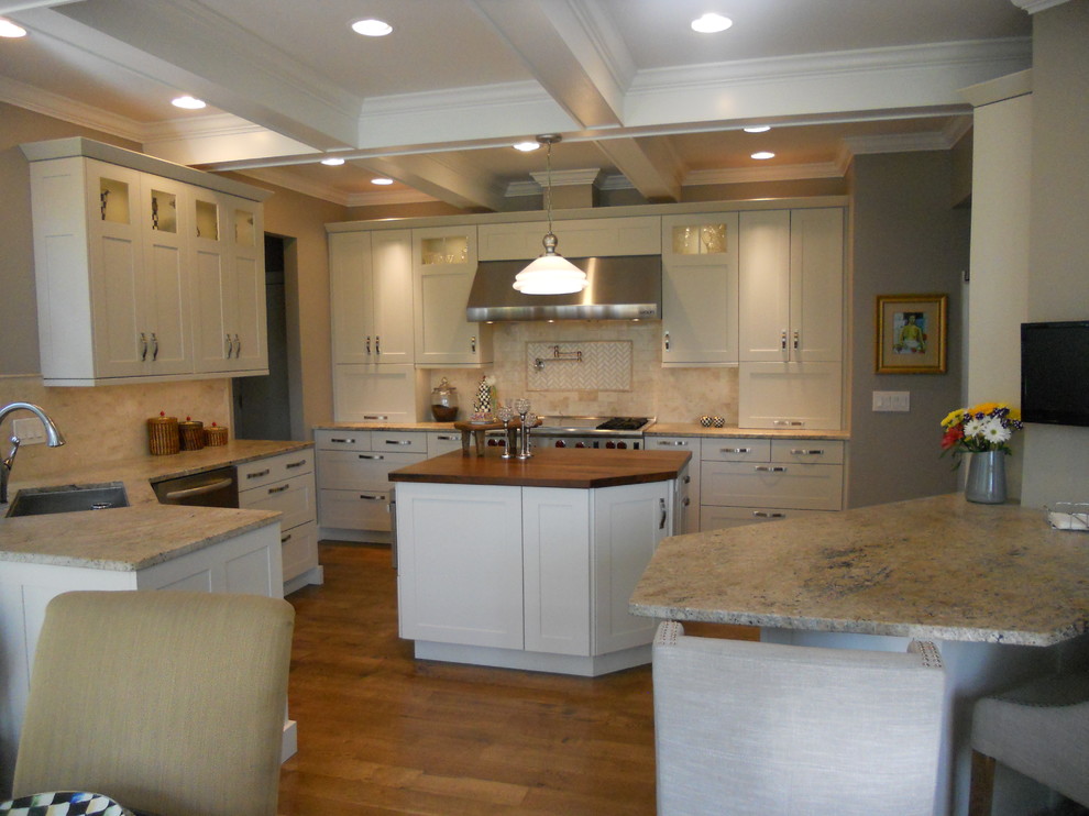 Example of a large transitional u-shaped medium tone wood floor eat-in kitchen design in New York with an undermount sink, recessed-panel cabinets, white cabinets, granite countertops, multicolored backsplash, porcelain backsplash, stainless steel appliances, gray walls and an island