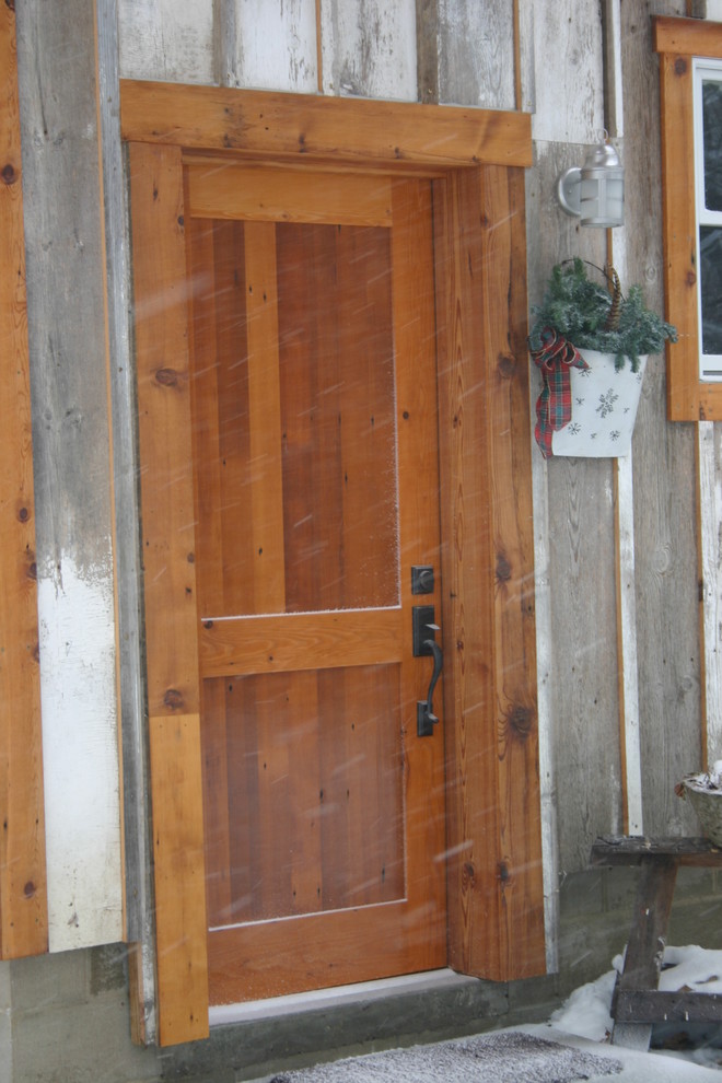 Mid-sized mountain style concrete floor front door photo with gray walls and a medium wood front door