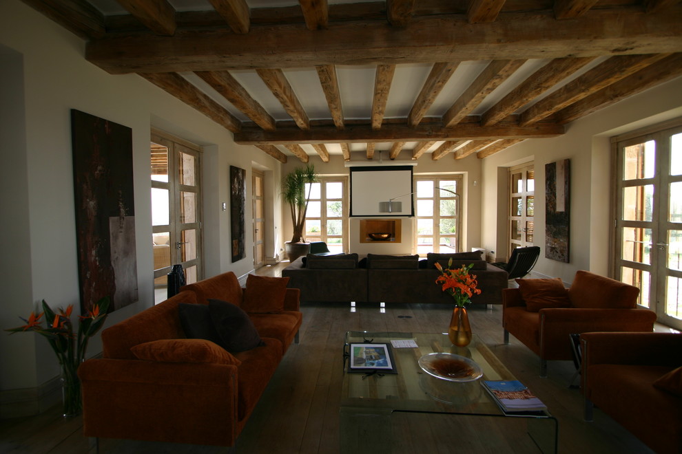 Diseño de salón abierto rústico grande con paredes beige, suelo de madera clara, suelo beige y televisor independiente