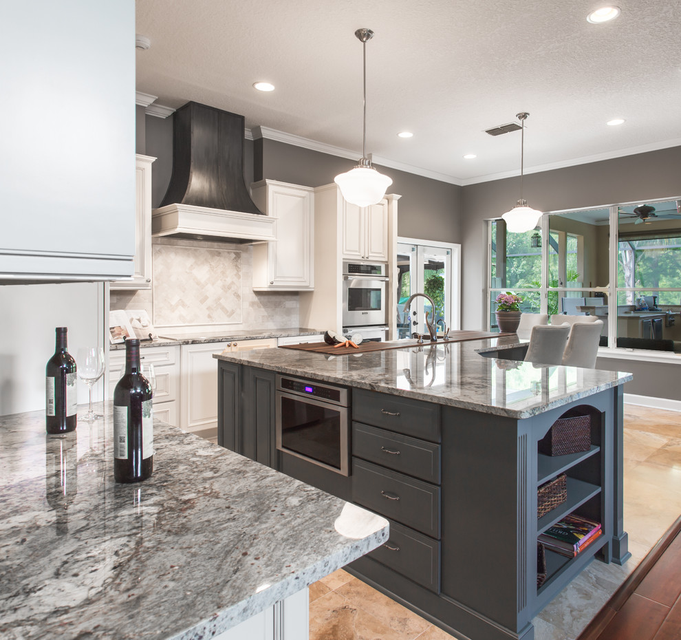 Photo of a mid-sized contemporary l-shaped eat-in kitchen in Jacksonville with a farmhouse sink, raised-panel cabinets, white cabinets, granite benchtops, beige splashback, stainless steel appliances and with island.