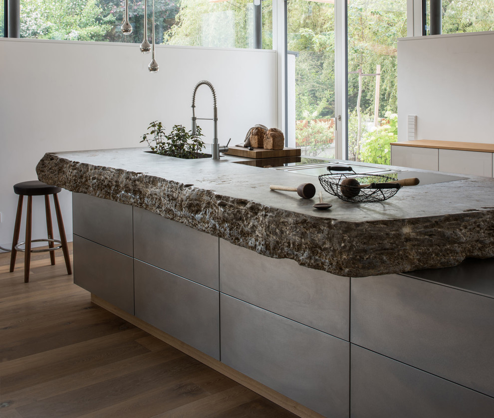 Design ideas for a large contemporary l-shaped kitchen in Munich with an integrated sink, flat-panel cabinets, limestone benchtops, white splashback, with island, grey cabinets, light hardwood floors and beige floor.
