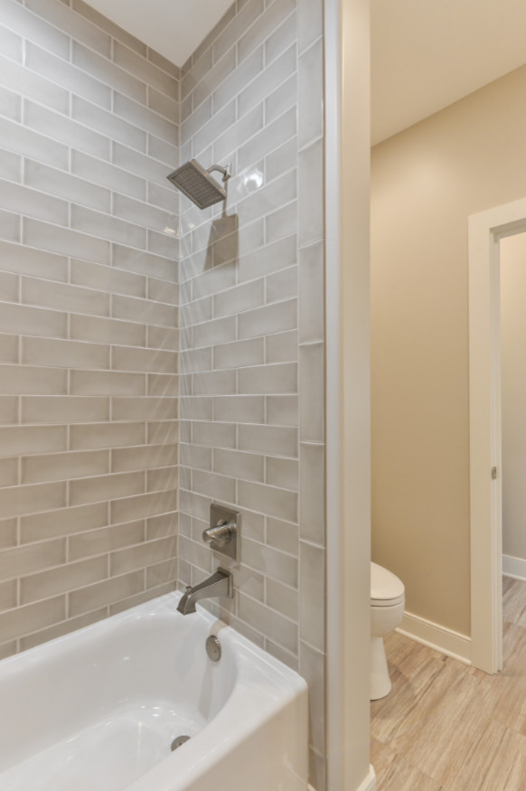 Mid-sized transitional kids bathroom in Louisville with flat-panel cabinets, white cabinets, a freestanding tub, a corner shower, gray tile, white tile, stone slab, white walls, vinyl floors, an undermount sink and marble benchtops.