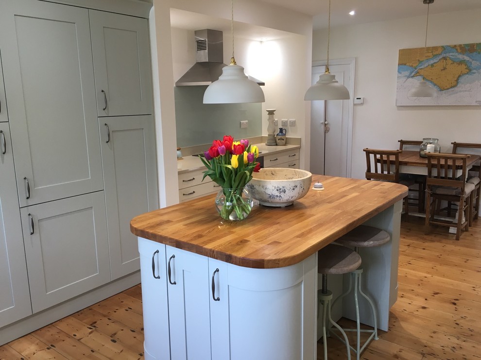 Design ideas for a large traditional kitchen in Hampshire with a farmhouse sink, shaker cabinets, blue cabinets, granite benchtops, glass sheet splashback, stainless steel appliances, medium hardwood floors and with island.