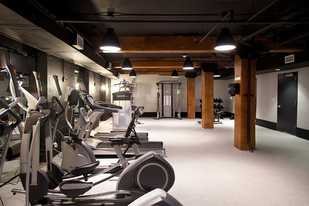 This is an example of a mid-sized industrial home gym in New York with beige walls and beige floor.