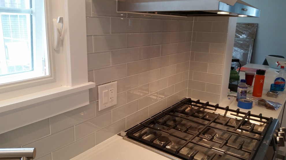 Mid-sized minimalist galley dark wood floor eat-in kitchen photo with an undermount sink, recessed-panel cabinets, white cabinets, granite countertops, white backsplash, glass tile backsplash, stainless steel appliances and a peninsula