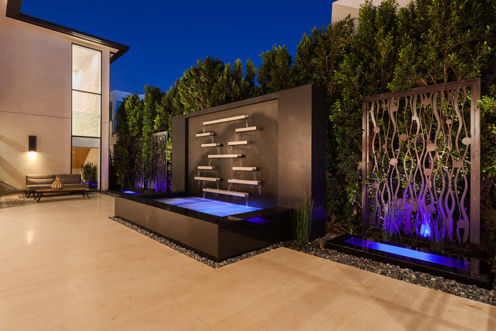 Inspiration for a large contemporary side yard patio in Orange County with a water feature, natural stone pavers and no cover.