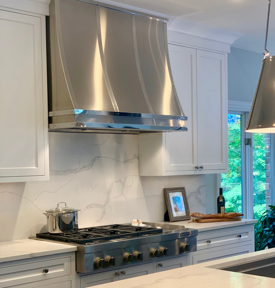 Eat-in kitchen - large transitional l-shaped medium tone wood floor and brown floor eat-in kitchen idea with an undermount sink, recessed-panel cabinets, white cabinets, quartz countertops, white backsplash, stone slab backsplash, stainless steel appliances, an island and white countertops