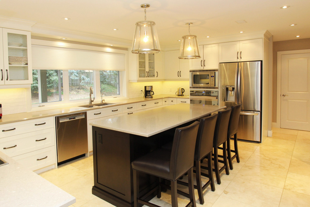 Large transitional u-shaped brown floor enclosed kitchen photo with an undermount sink, white cabinets, granite countertops, white backsplash, stainless steel appliances, an island and shaker cabinets
