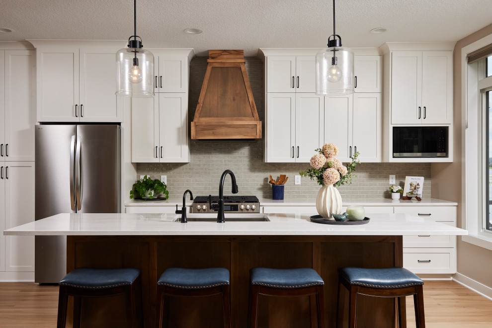 Inspiration for a mid-sized transitional galley vinyl floor and brown floor open concept kitchen remodel in Minneapolis with an undermount sink, shaker cabinets, white cabinets, quartz countertops, green backsplash, subway tile backsplash, stainless steel appliances, an island and white countertops