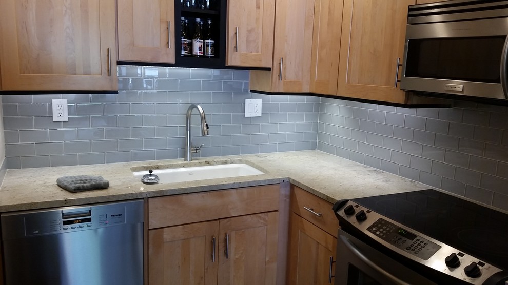 Enclosed kitchen - mid-sized transitional l-shaped enclosed kitchen idea in Seattle with an undermount sink, shaker cabinets, light wood cabinets, granite countertops, blue backsplash, glass tile backsplash and stainless steel appliances