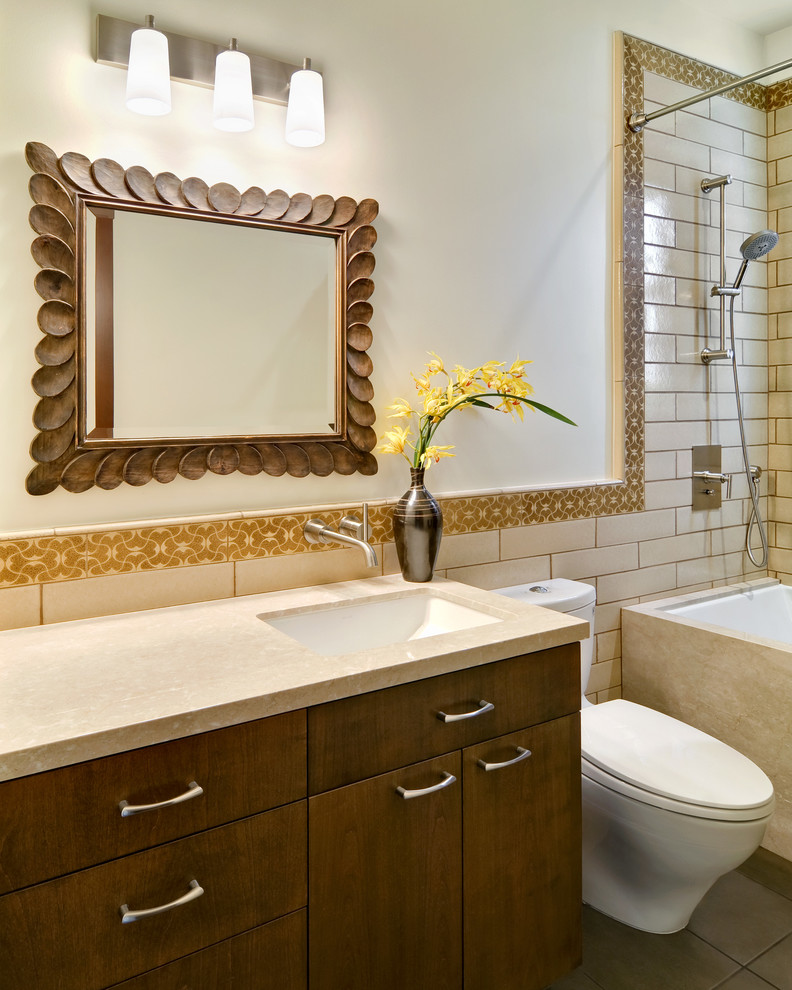 This is an example of a small mediterranean bathroom in San Francisco with an undermount sink, an undermount tub, a shower/bathtub combo, a two-piece toilet, yellow tile, subway tile, white walls, porcelain floors, flat-panel cabinets, medium wood cabinets and marble benchtops.