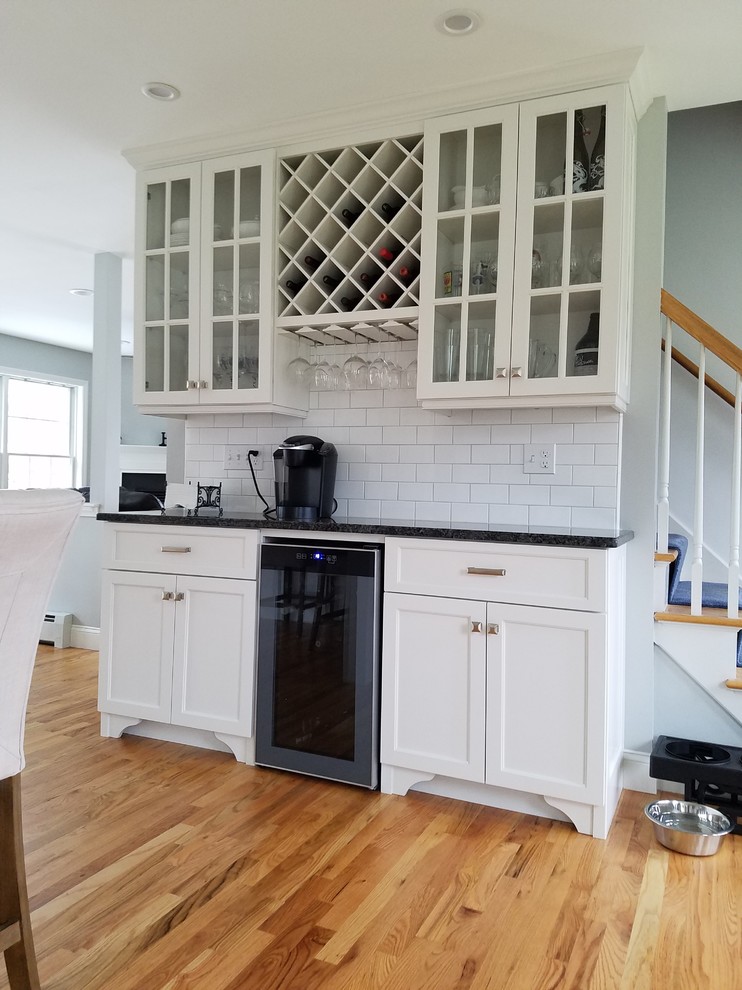 Eat-in kitchen - large transitional l-shaped light wood floor and brown floor eat-in kitchen idea with an undermount sink, shaker cabinets, white cabinets, granite countertops, white backsplash, subway tile backsplash, stainless steel appliances and an island