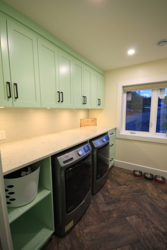 Example of a large minimalist galley vinyl floor and brown floor dedicated laundry room design in Other with an undermount sink, shaker cabinets, green cabinets, solid surface countertops, white backsplash, subway tile backsplash, white walls, a side-by-side washer/dryer and green countertops
